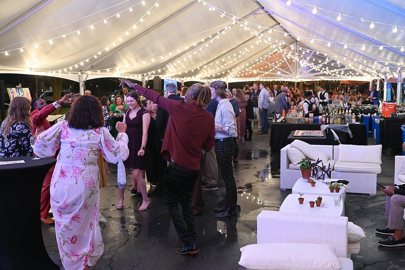 People dancing under a white tent with string lights